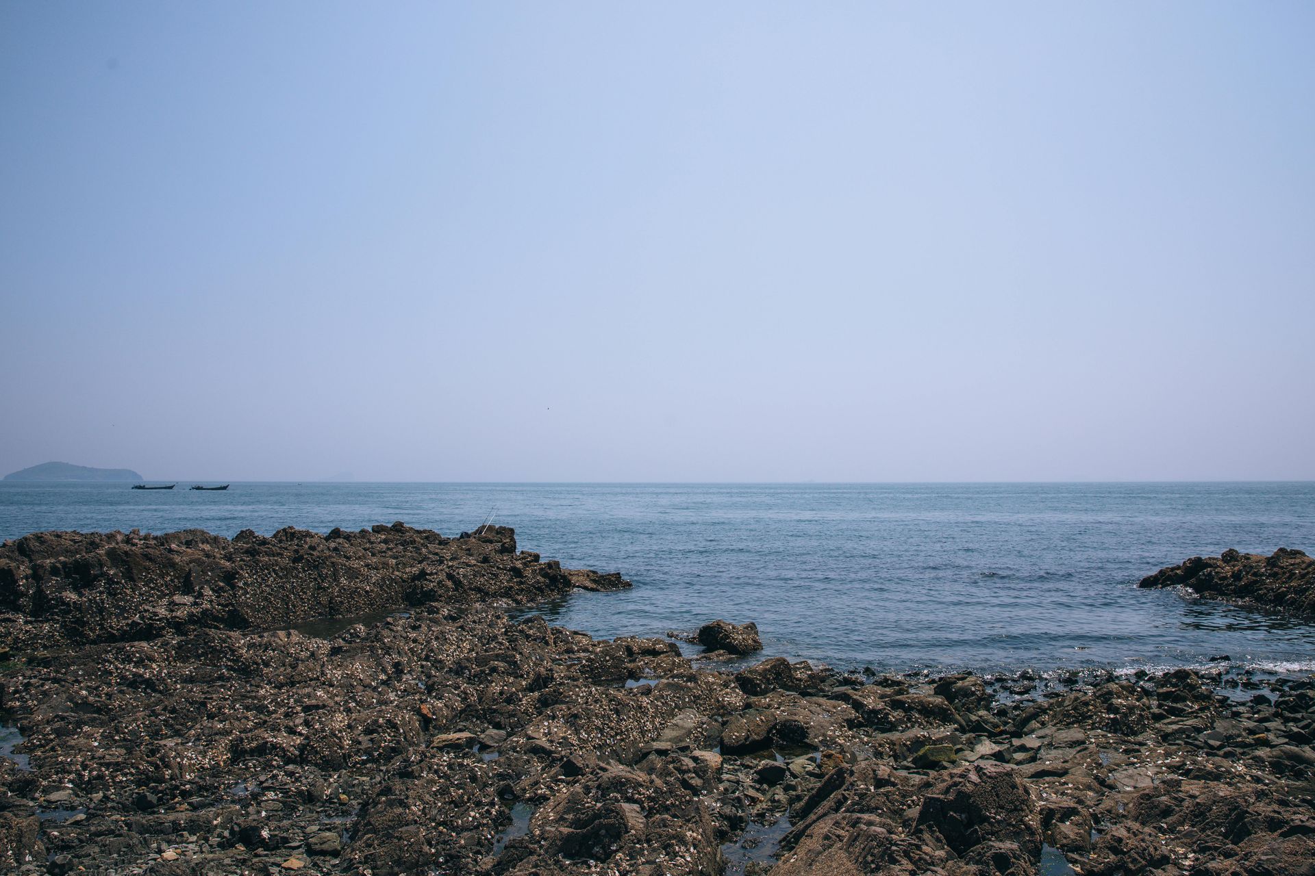 A rocky beach with a view of the ocean on a sunny day.
