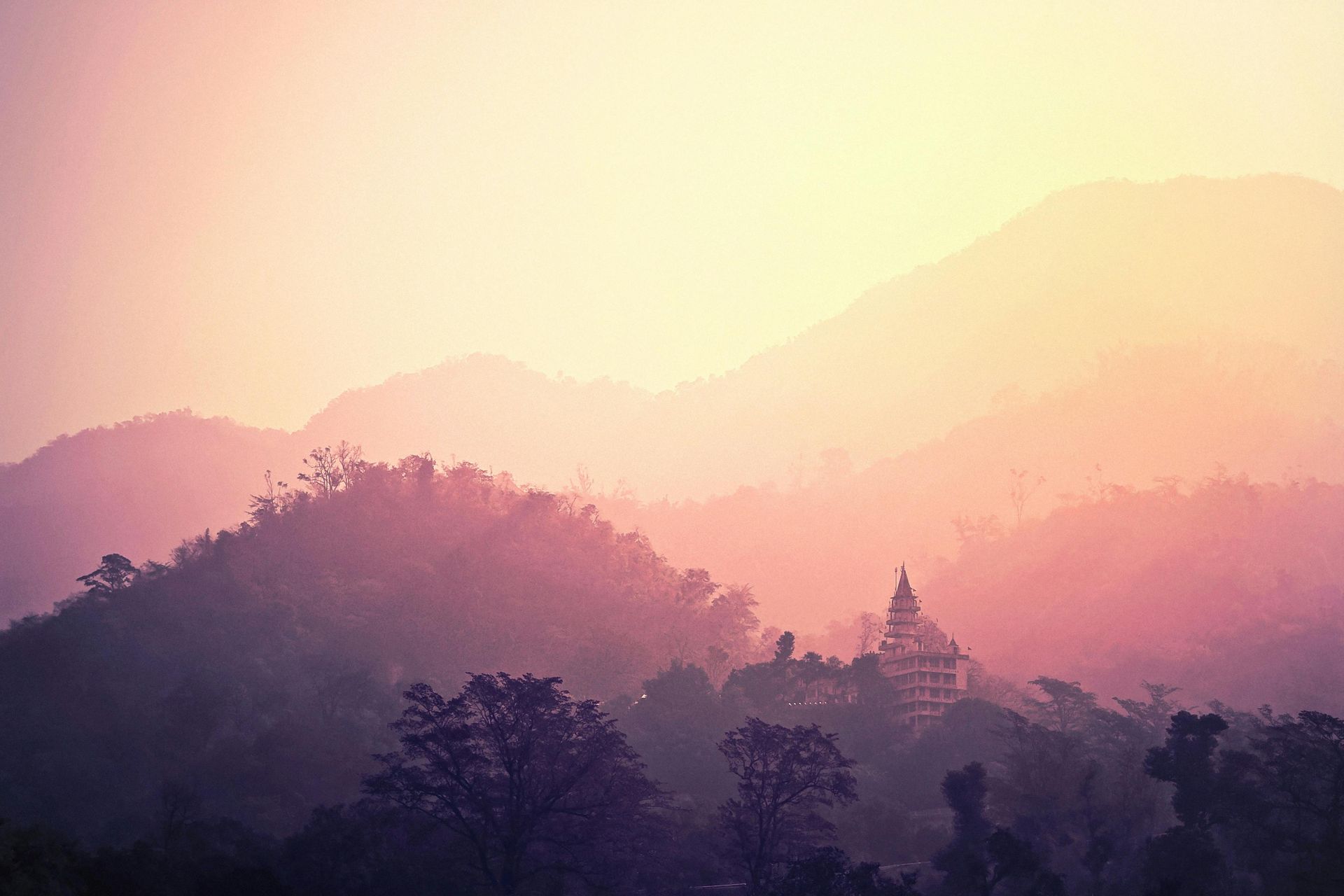 A silhouette of a temple on top of a mountain at sunset.