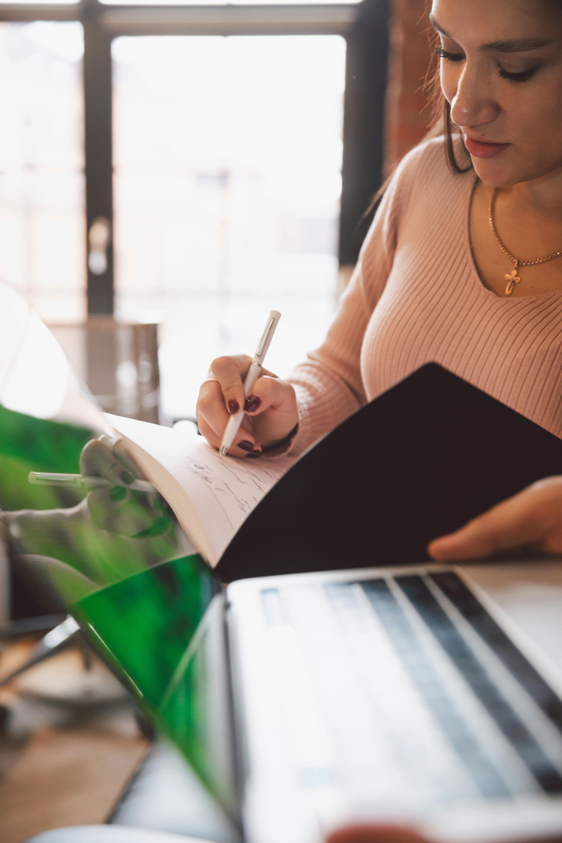 A woman is sitting at a table writing in a notebook.
