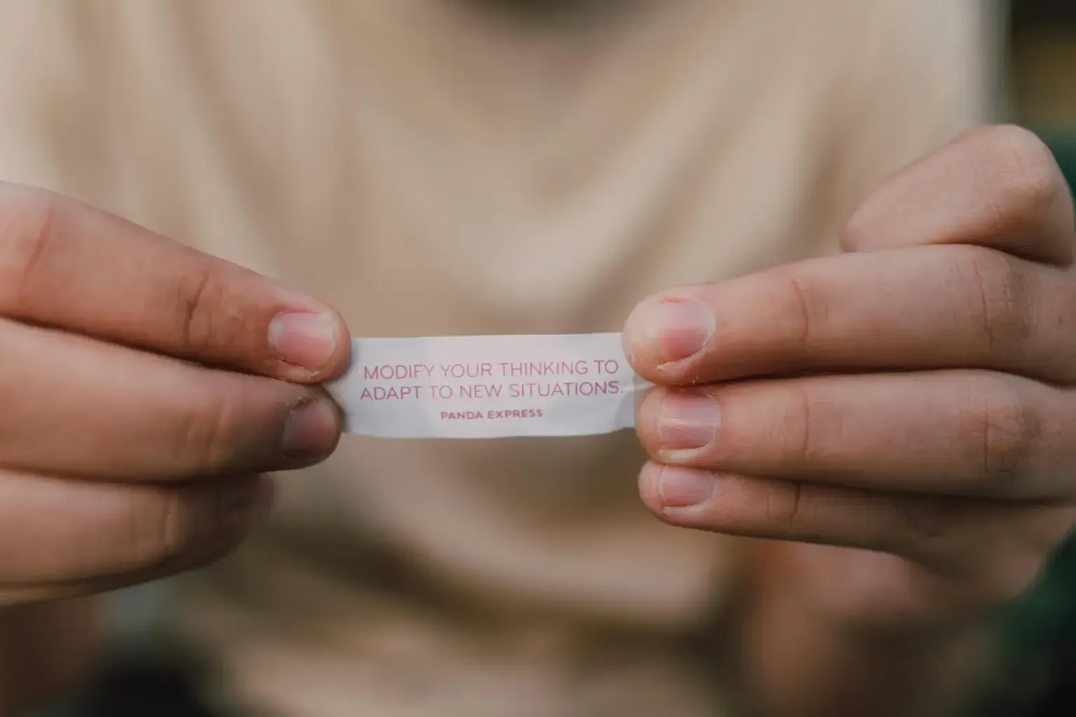 A person is holding a fortune cookie in their hands.