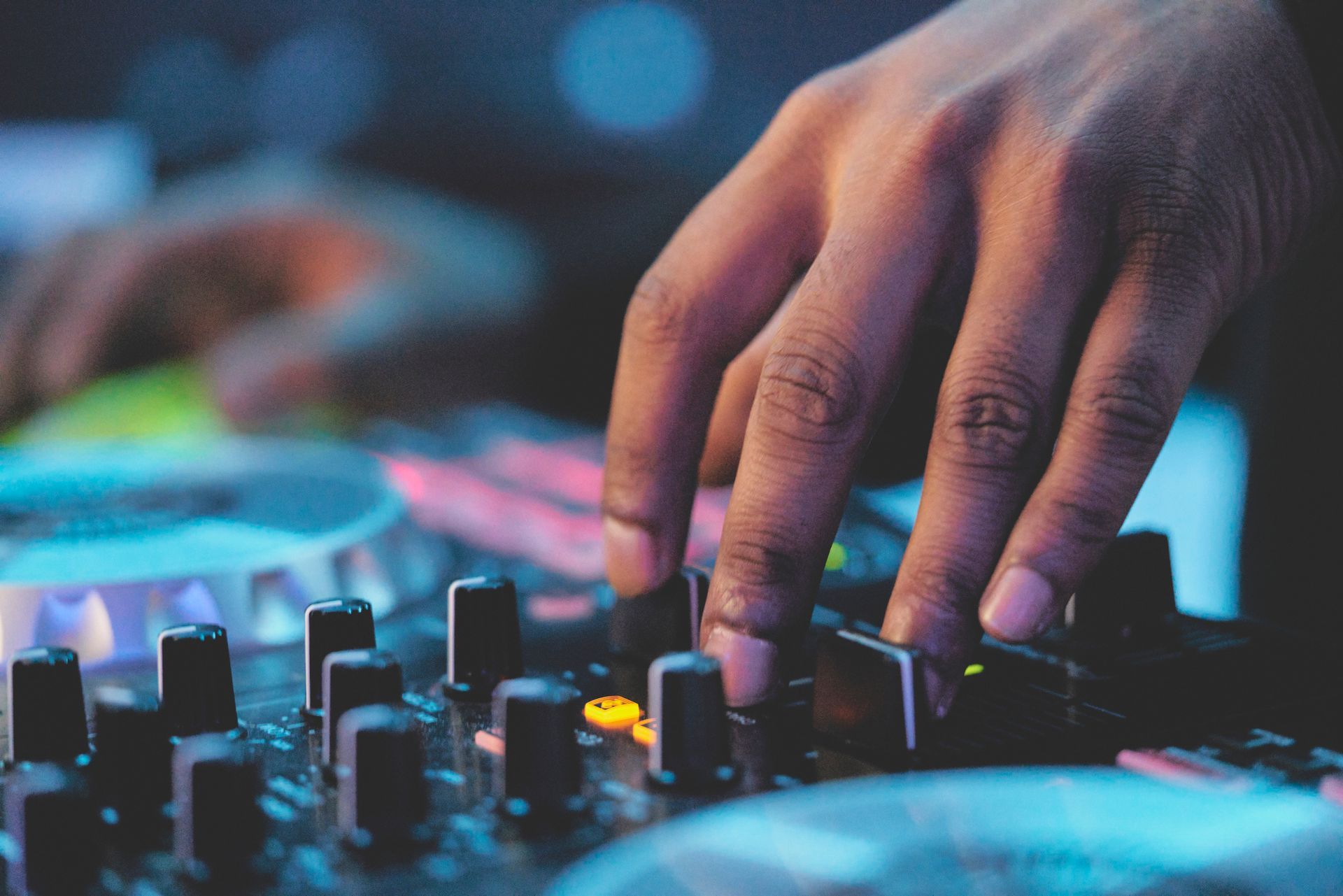 A close up of a dj 's hands playing music on a mixer.