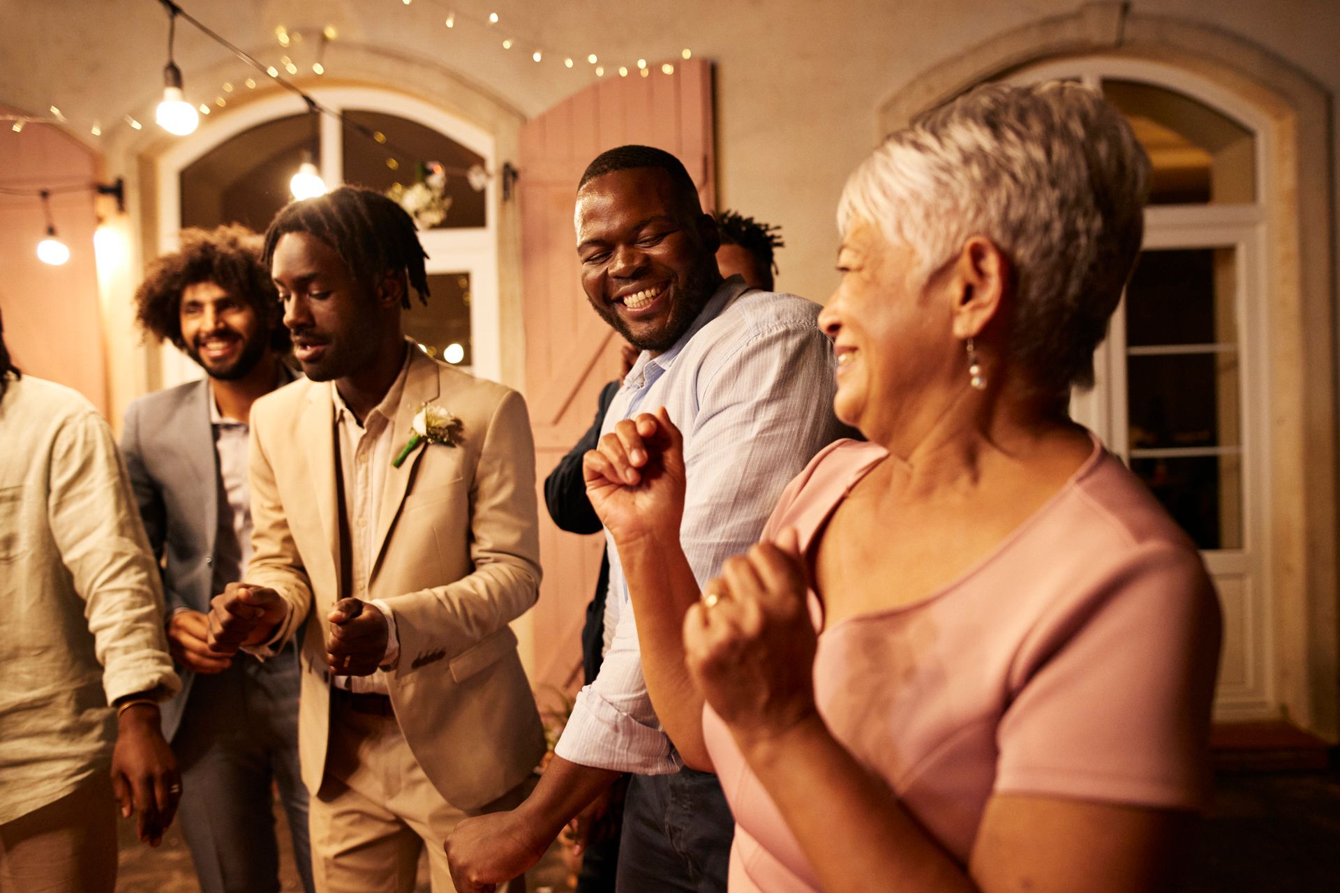 A group of people are dancing at a wedding reception.