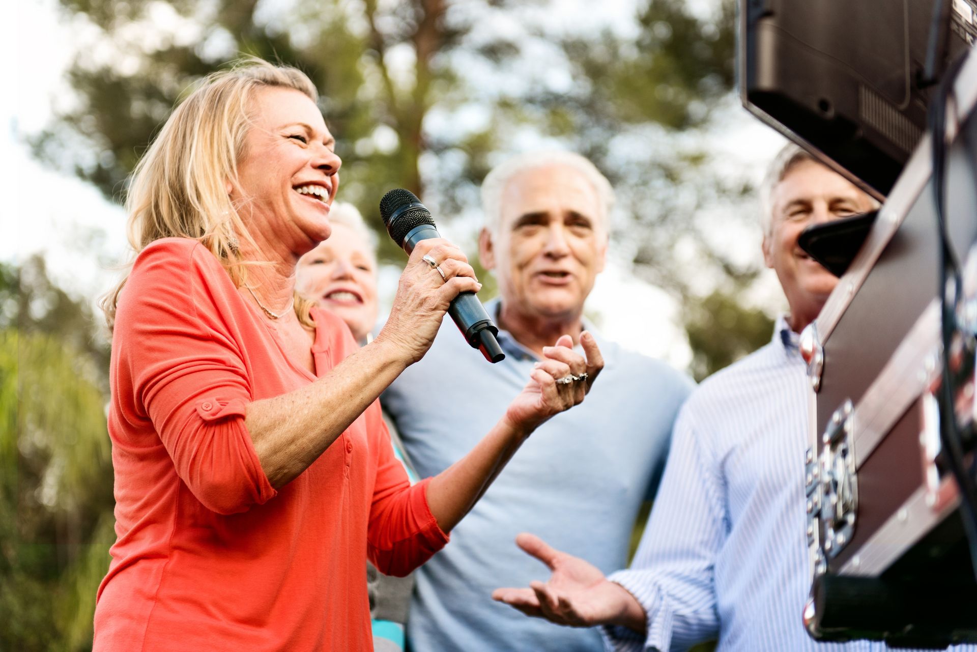 A woman is singing into a microphone in front of a group of people.