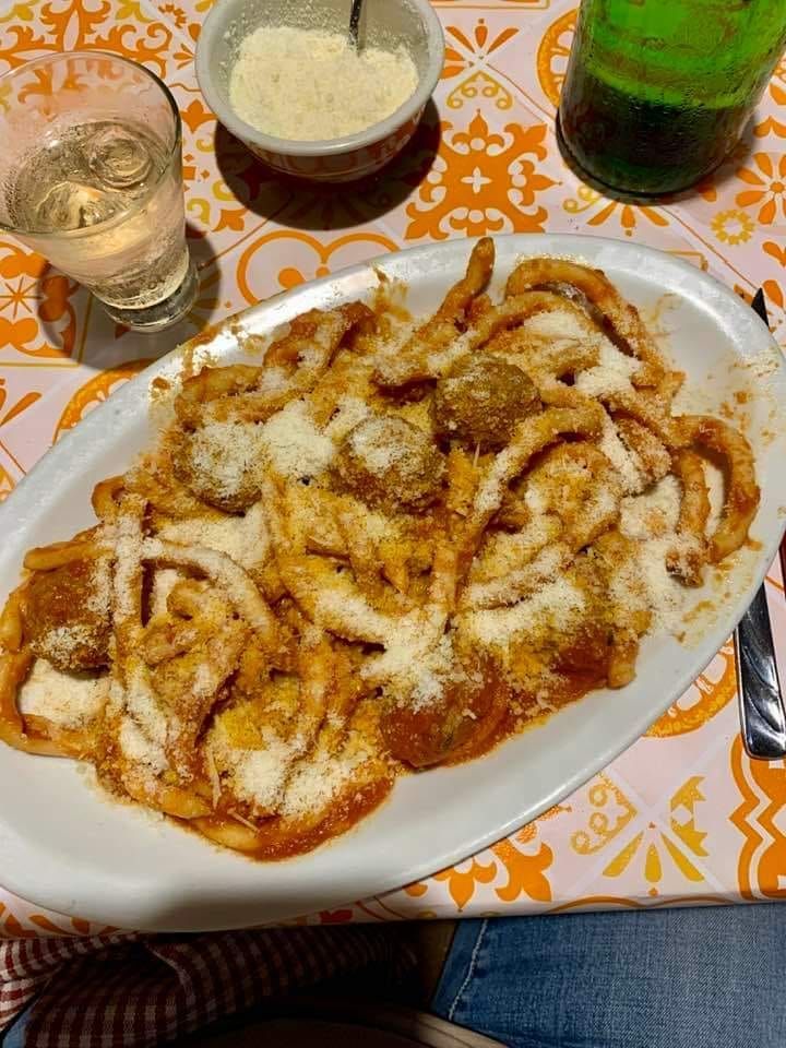 Piatto di pasta con polpette e parmigiano su un piatto bianco.