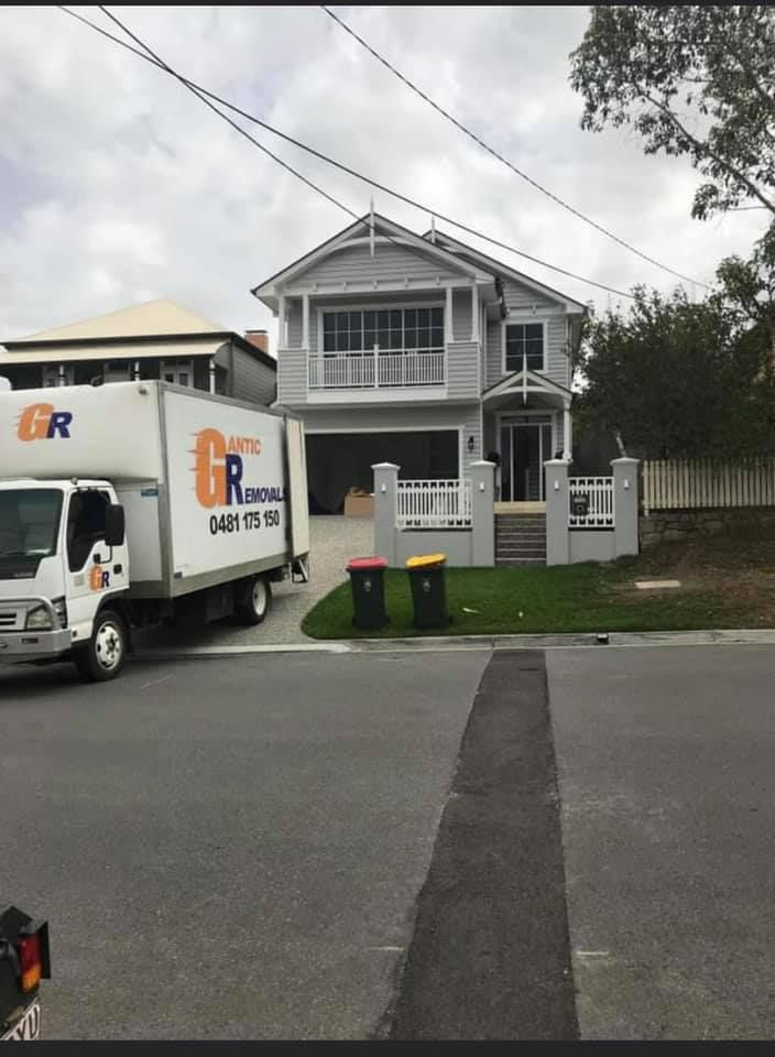 Moving truck in front of a gray house with a garage, front steps, and balcony under an overcast sky. — Gantic Removals Ipswich in Ipswich, QLD