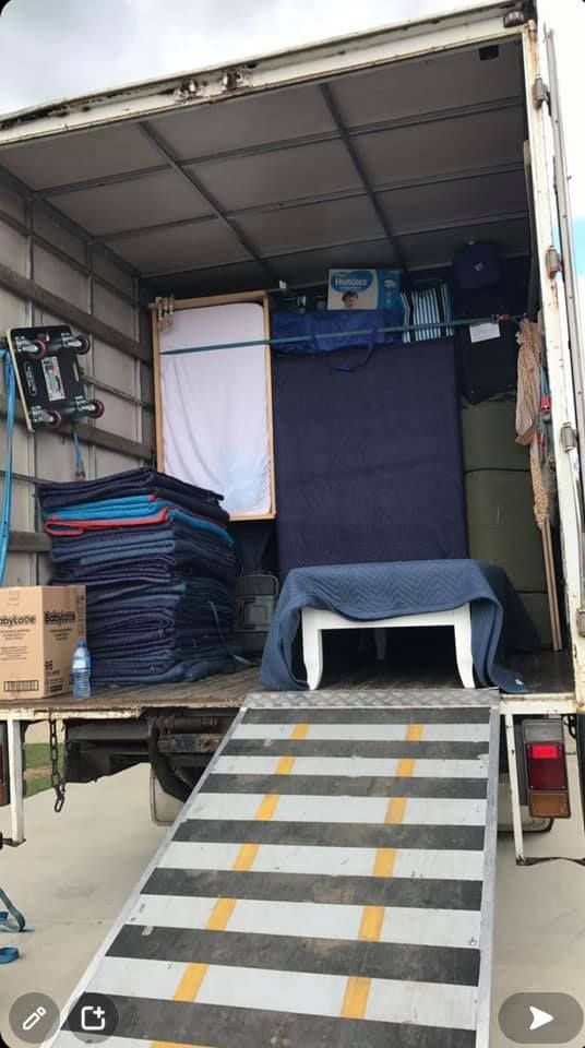 Inside of a moving truck filled with furniture, blankets, boxes, and a white table. Ramp is down. — Gantic Removals Ipswich in Ipswich, QLD