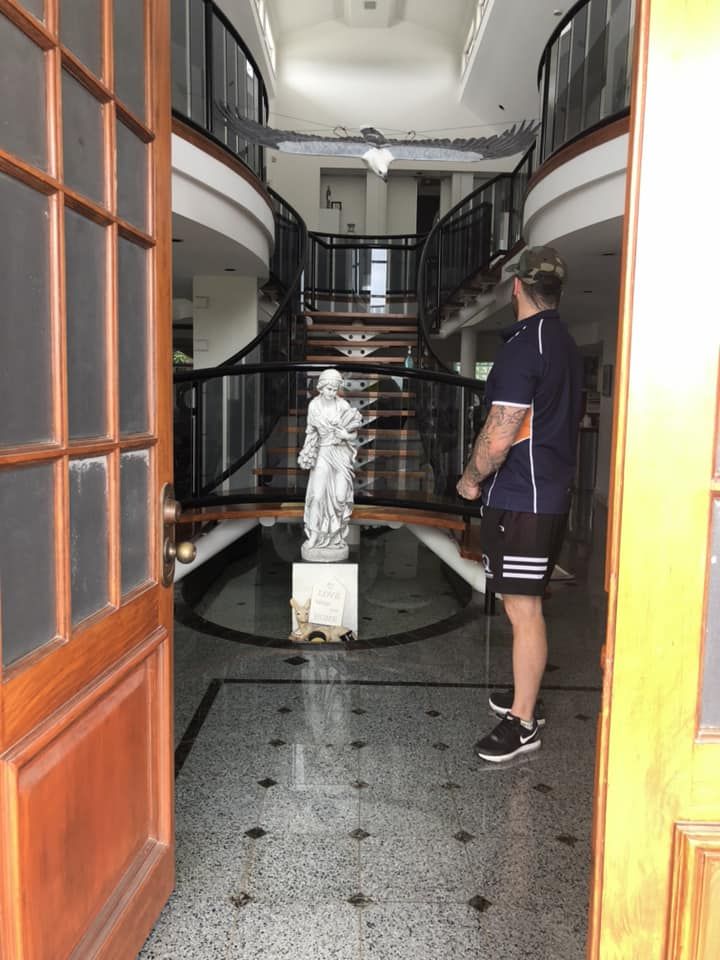 Man stands in doorway, looking at statue and staircase in a building. Wooden doors. Interior has multiple levels. — Gantic Removals Ipswich in Ipswich, QLD