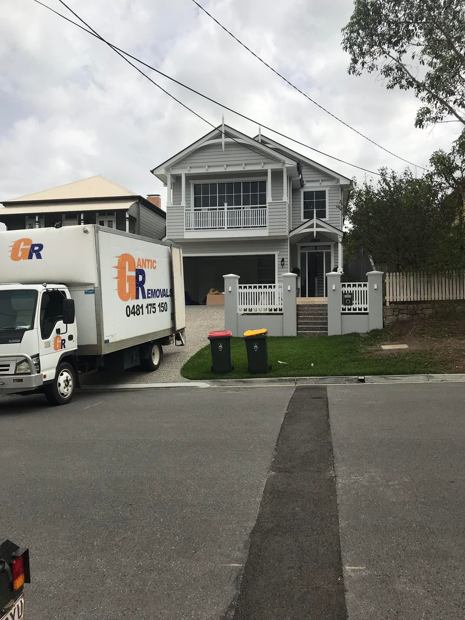 A two-story gray house with a moving truck parked in front. — Gantic Removals Ipswich in Ipswich, QLD