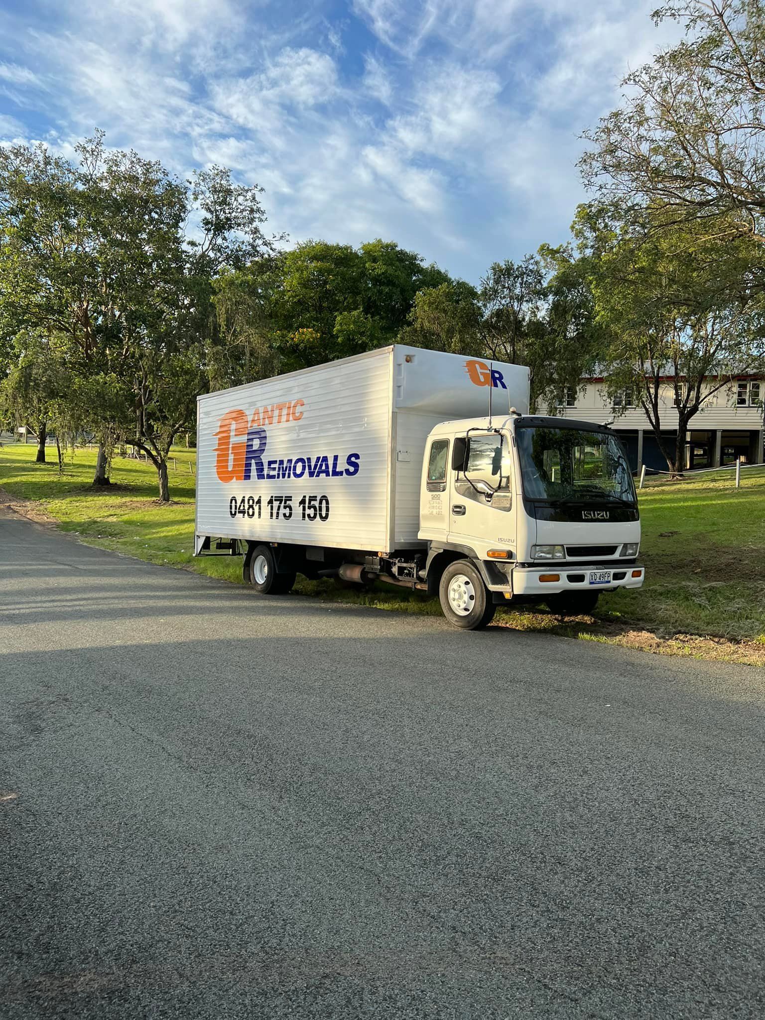 White moving truck parked on a gravel path near green grass and trees on a sunny day. — Gantic Removals Ipswich in Ipswich, QLD