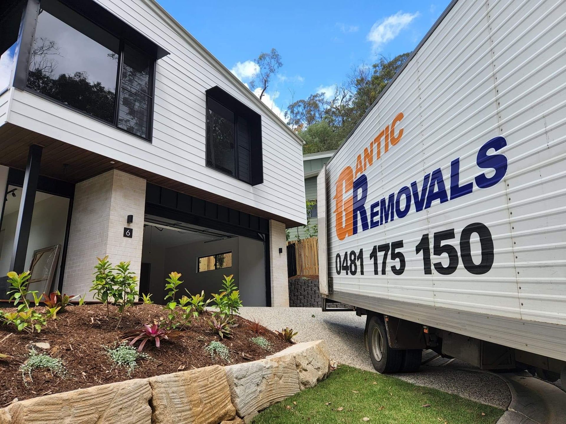 Removal truck parked in front of a modern white house with an open garage — Gantic Removals Ipswich in Ipswich, QLD