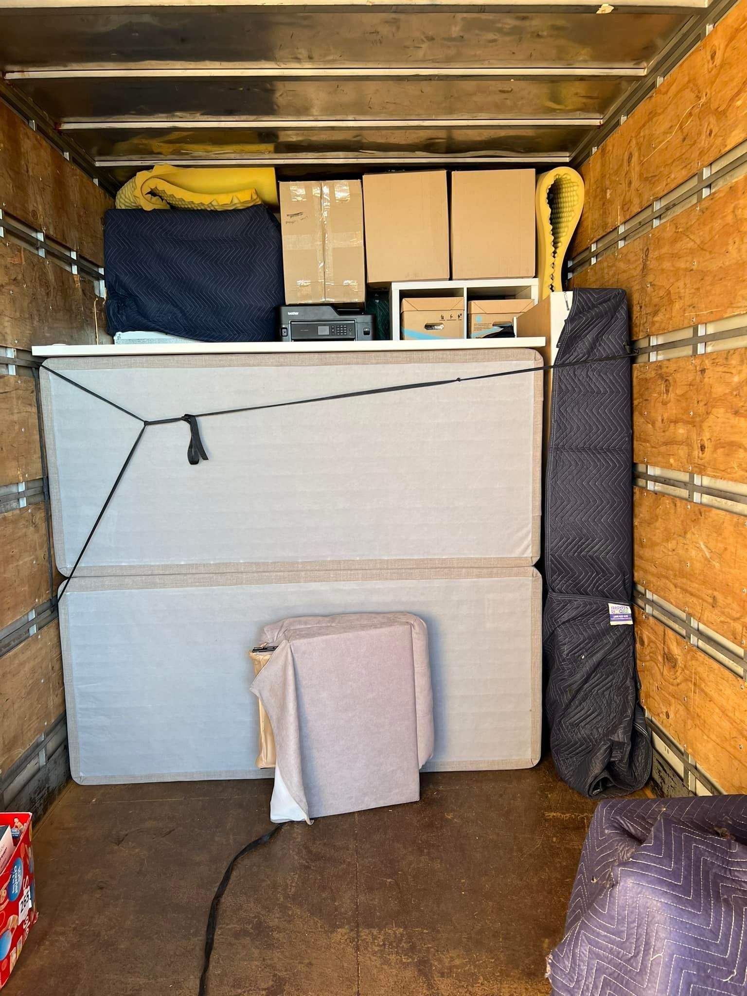 Inside a moving truck: mattresses, boxes, furniture, and packing materials secured with straps. — Gantic Removals Ipswich in Ipswich, QLD