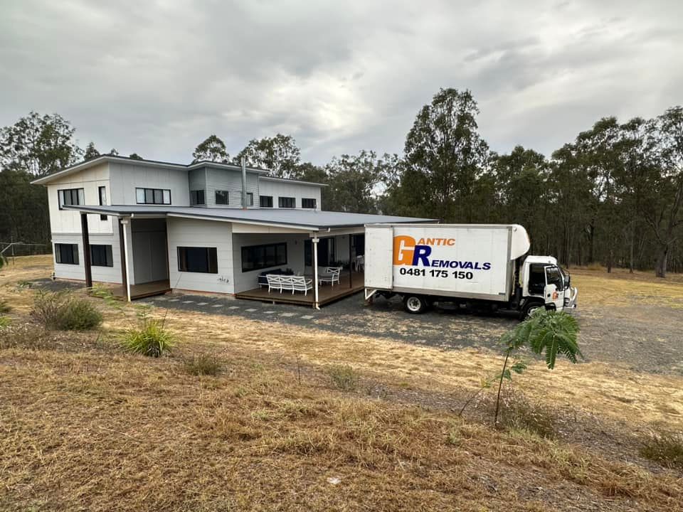 White truck with attached equipment parked on a gravel lot under a cloudy sky. — Gantic Removals Ipswich in Ipswich, QLD