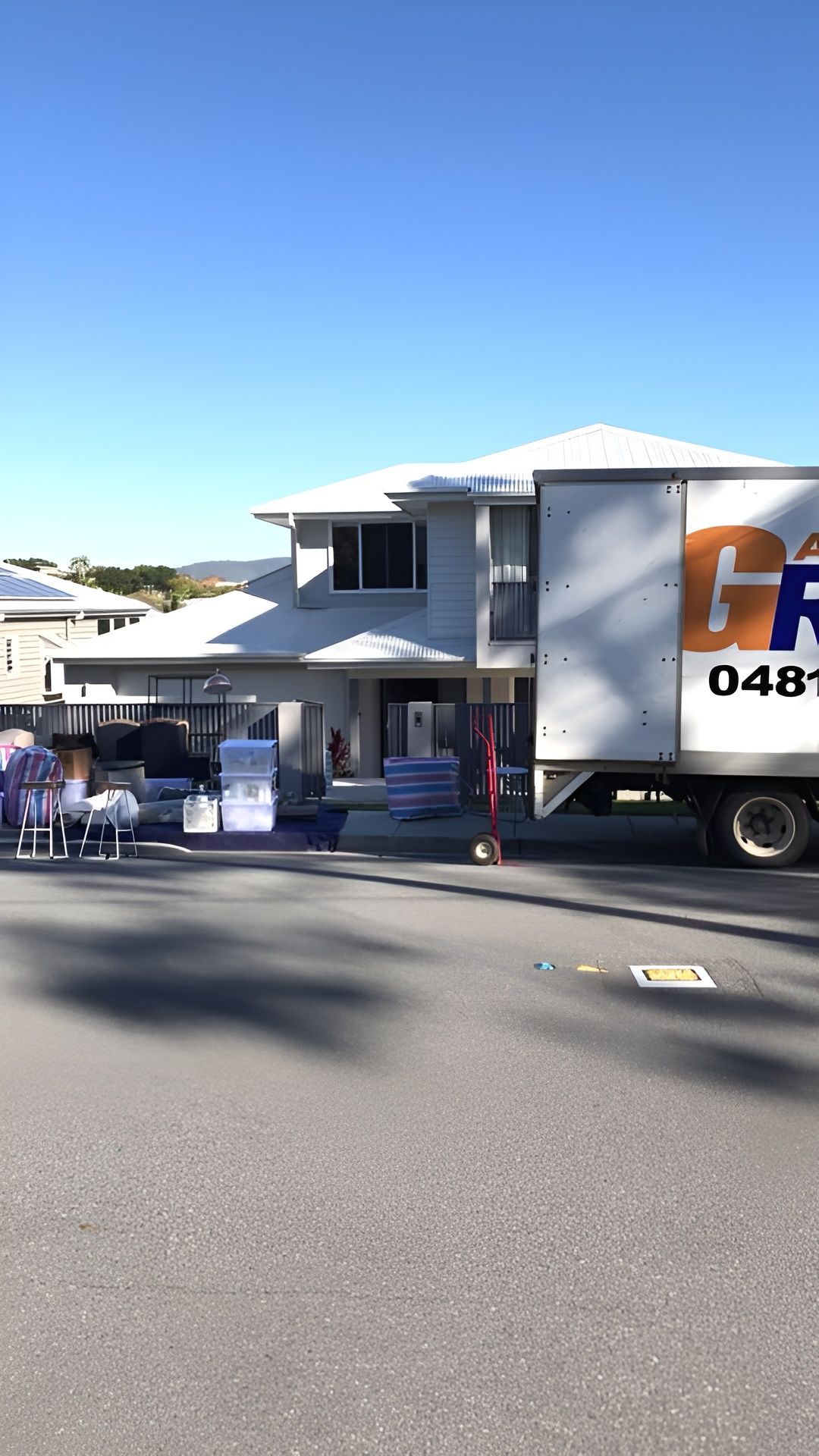 Moving truck parked in front of a two-story house, unloading furniture on a sunny day. — Gantic Removals Ipswich in Ipswich, QLD