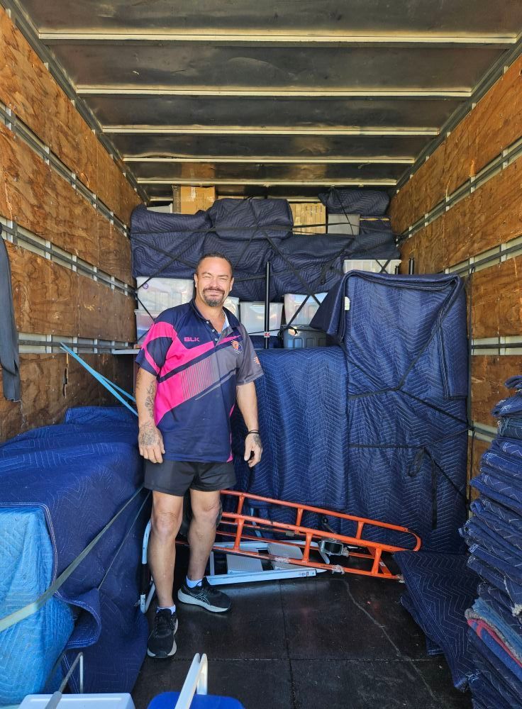 Man stands in a moving truck filled with furniture wrapped in blue pads. — Gantic Removals Ipswich in Ipswich, QLD