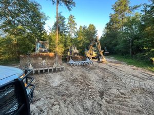 A bulldozer is driving down a dirt road next to a truck.