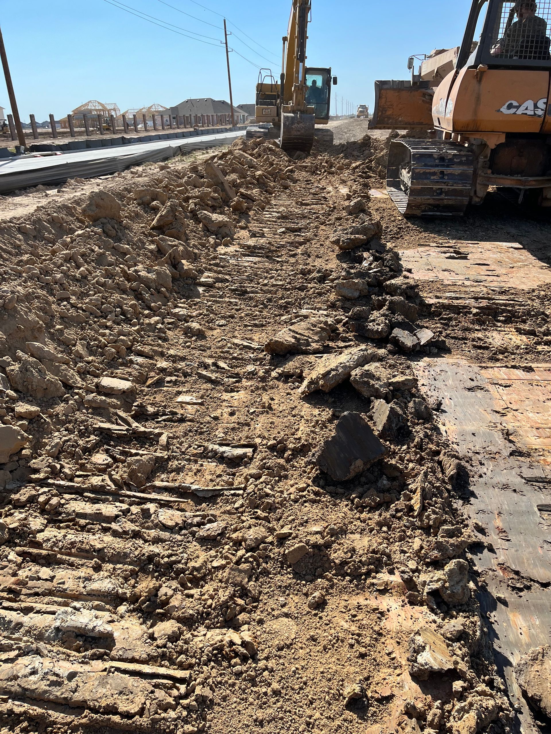 A construction site with a lot of dirt and a bulldozer in the background.