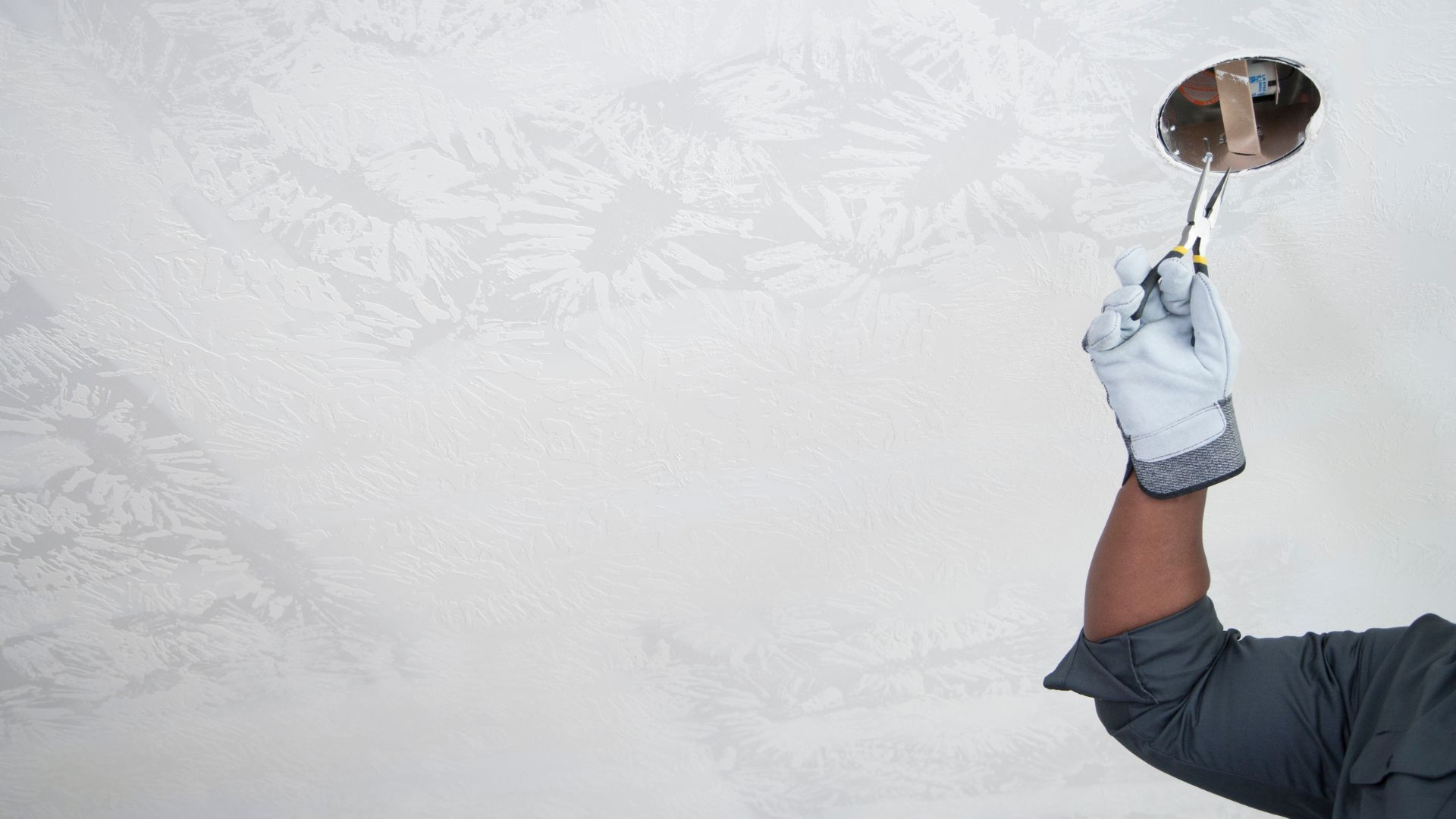 A man is holding a brush over his head while painting a wall.