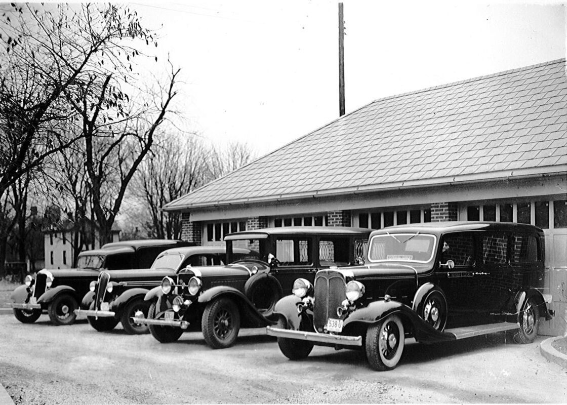 A row of old cars are parked in front of a building
