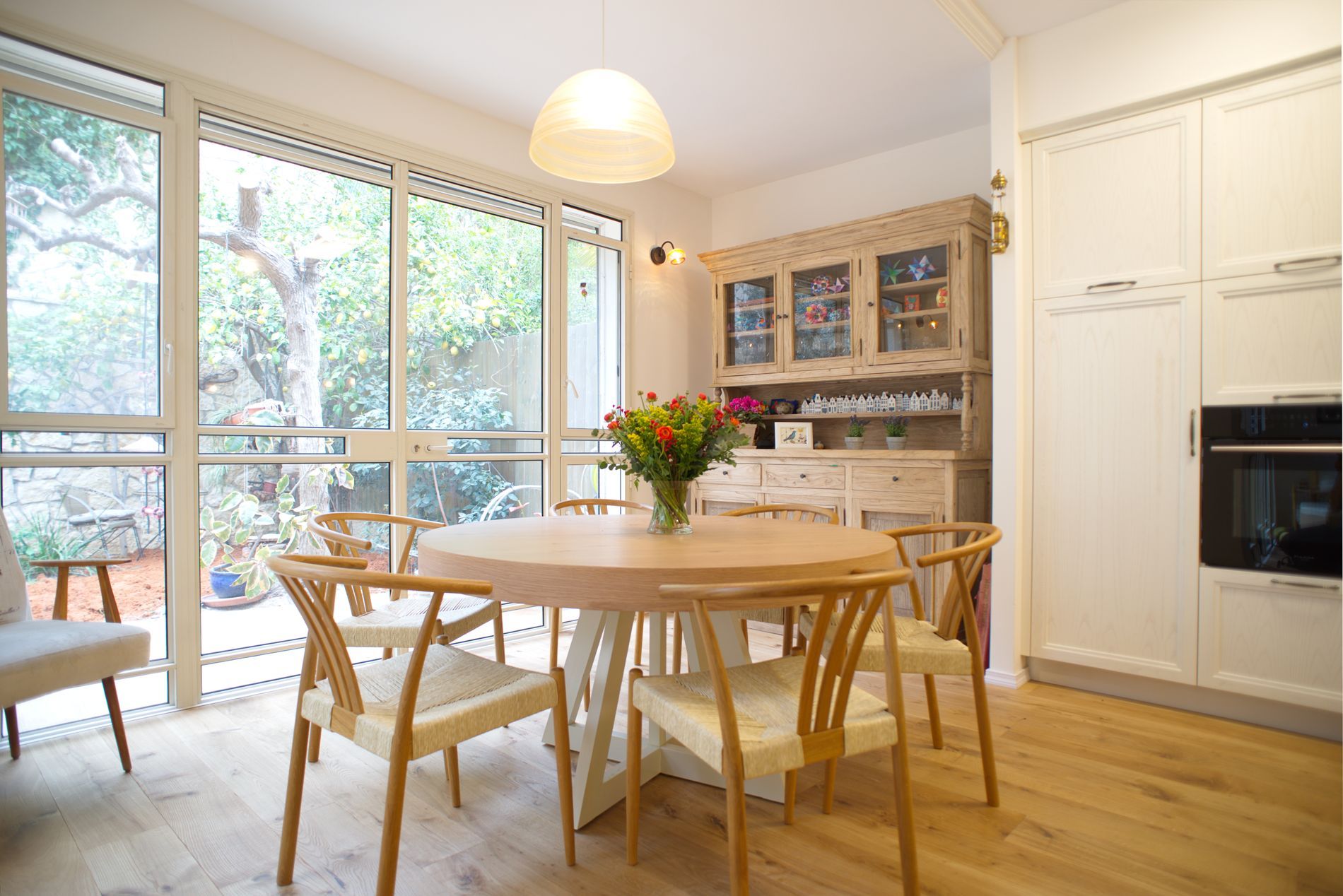 חדר אוכל עם שולחן וכיסאות ואגרטל פרחים.