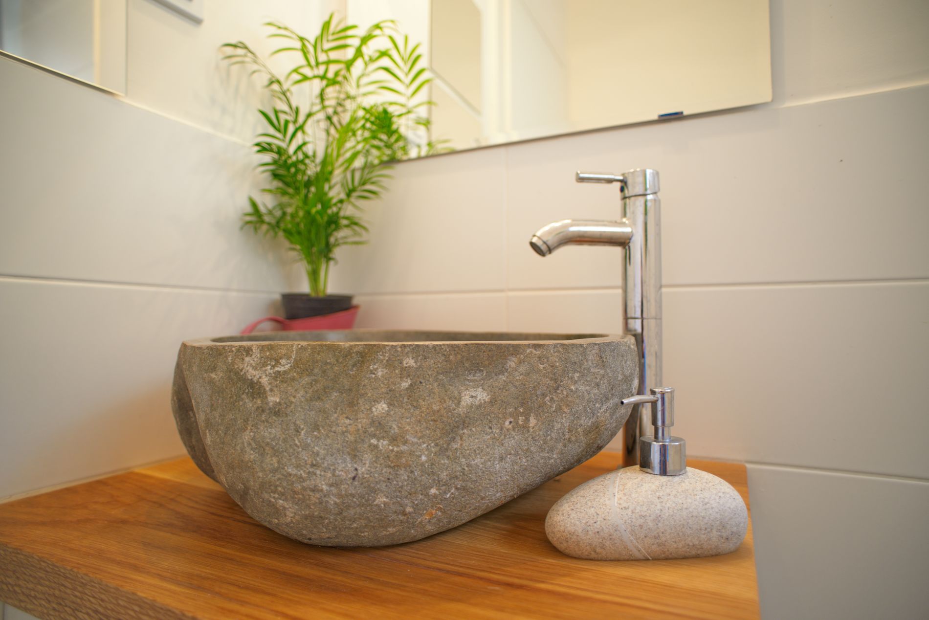 כיור אמבטיה יושב על דלפק עץ ליד צמח.