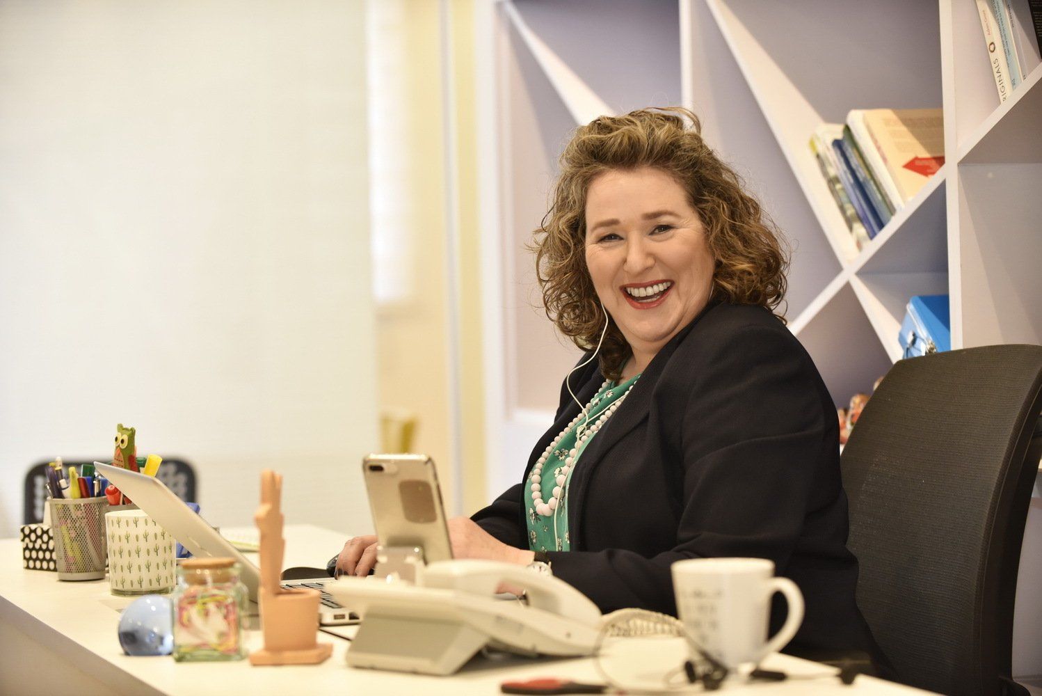 אישה יושבת ליד שולחן עם מחשב נייד וטלפון.