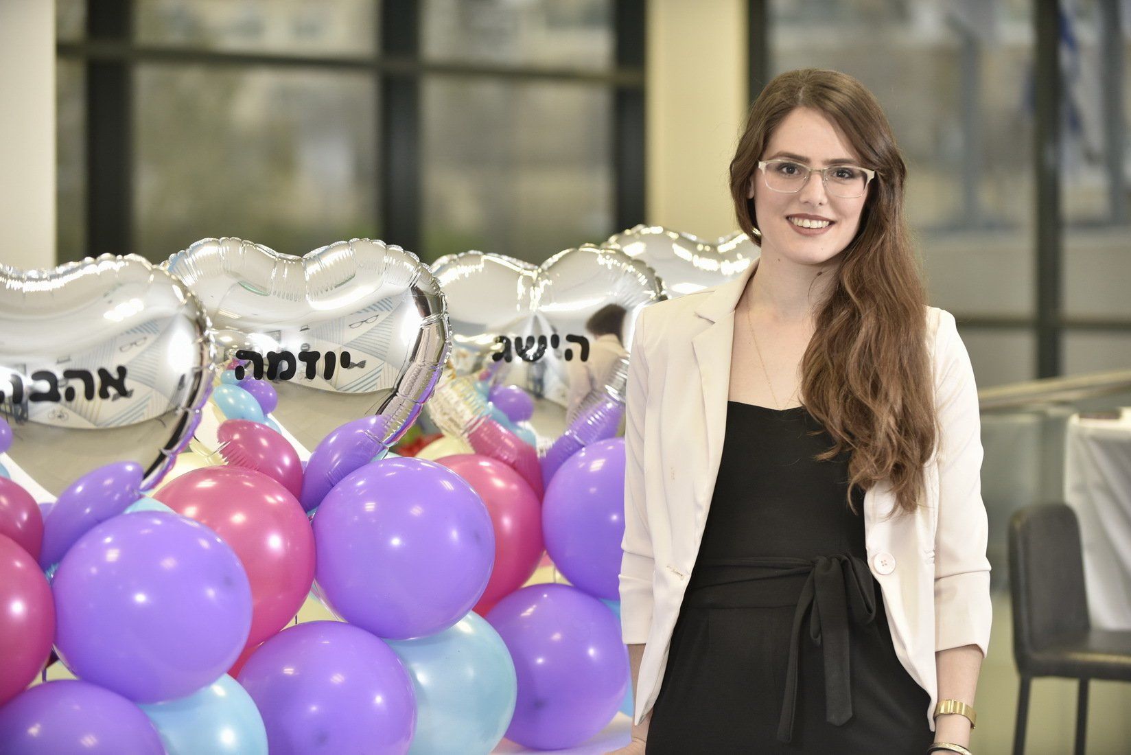 אישה עומדת מול חבורה של בלונים.