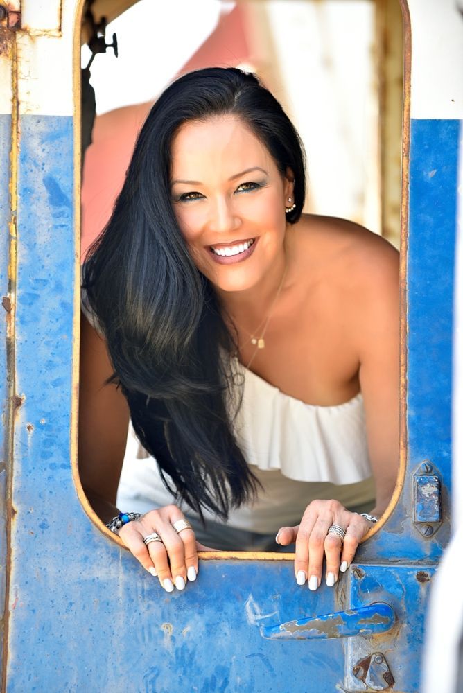 אישה מביטה מבעד לדלת כחולה ומחייכת.