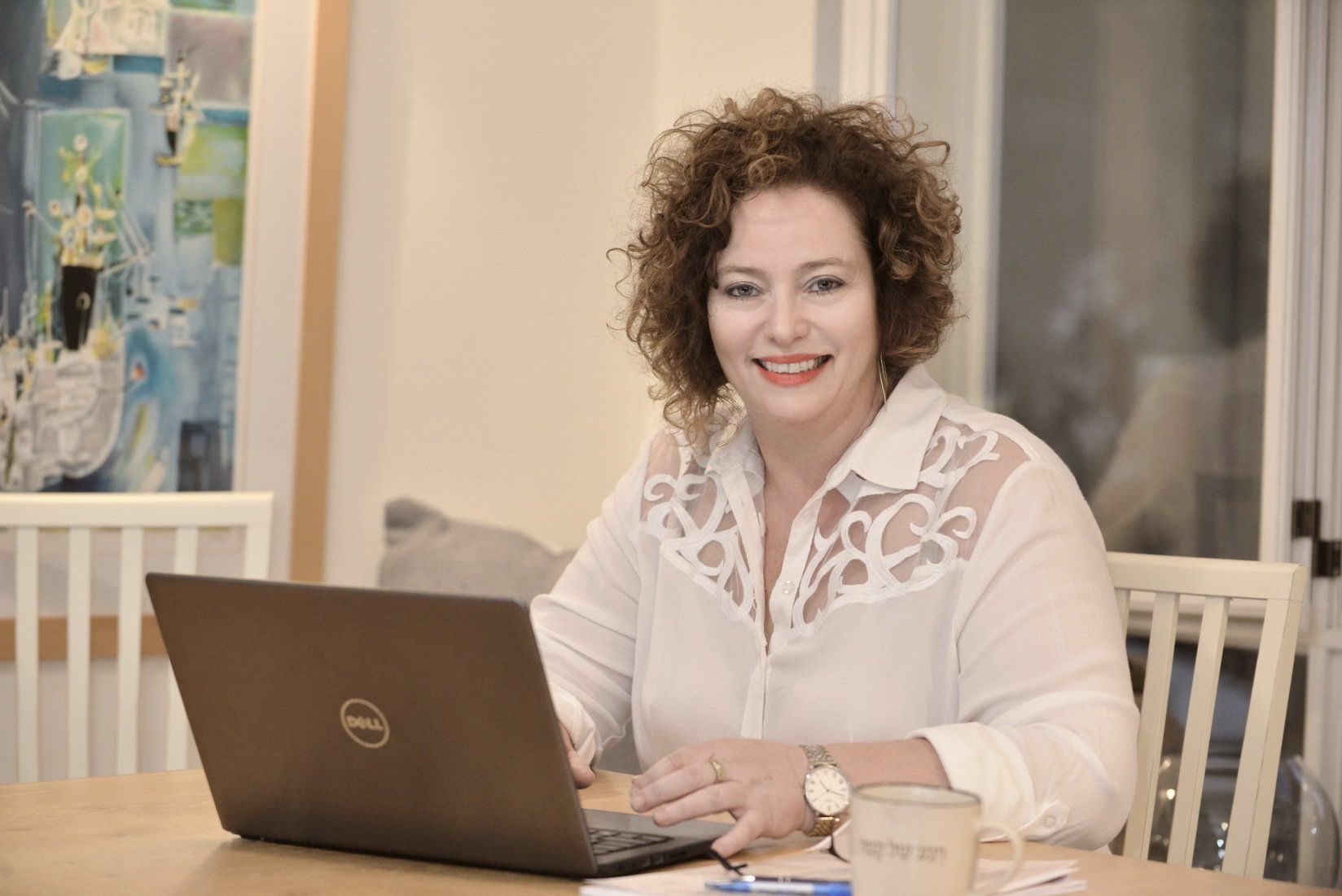 אישה יושבת ליד שולחן באמצעות מחשב נייד.