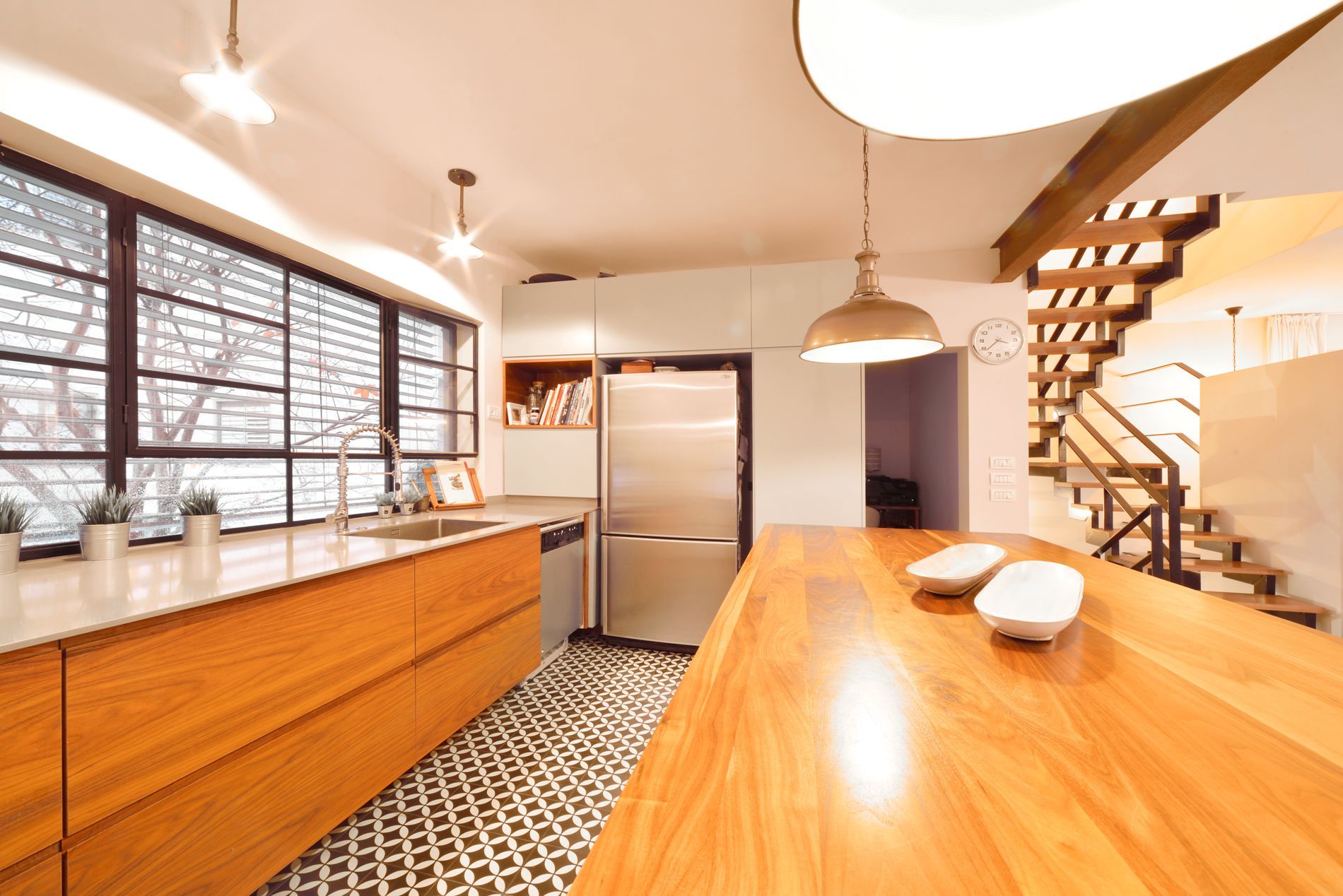 מטבח עם שולחן עץ גדול, מכשירי נירוסטה וגרם מדרגות.