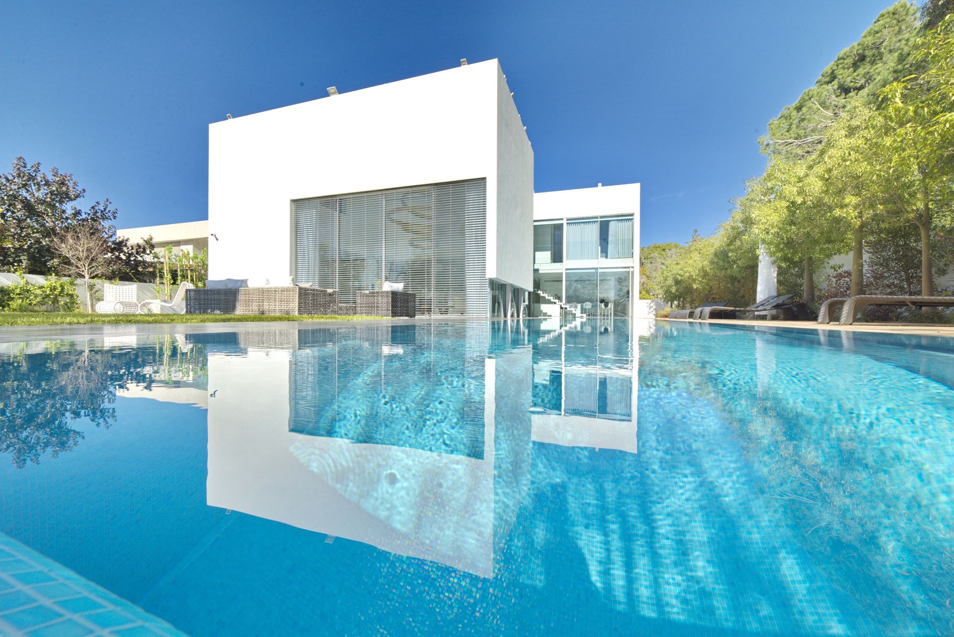 בית לבן עם בריכת שחייה גדולה מולו