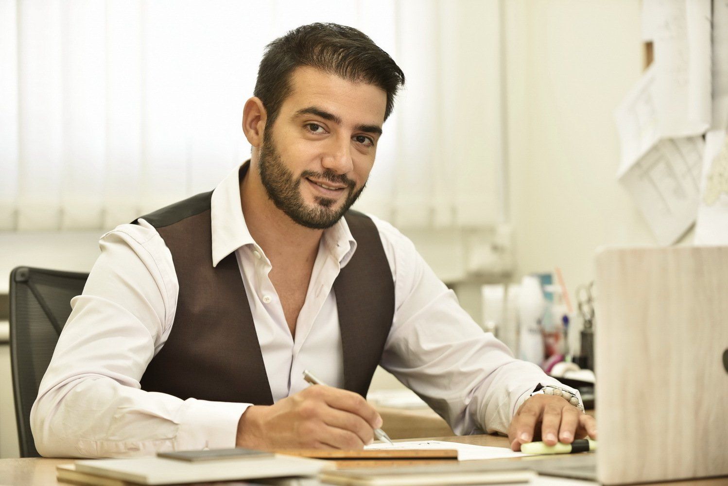 גבר יושב ליד שולחן מול מחשב נייד.