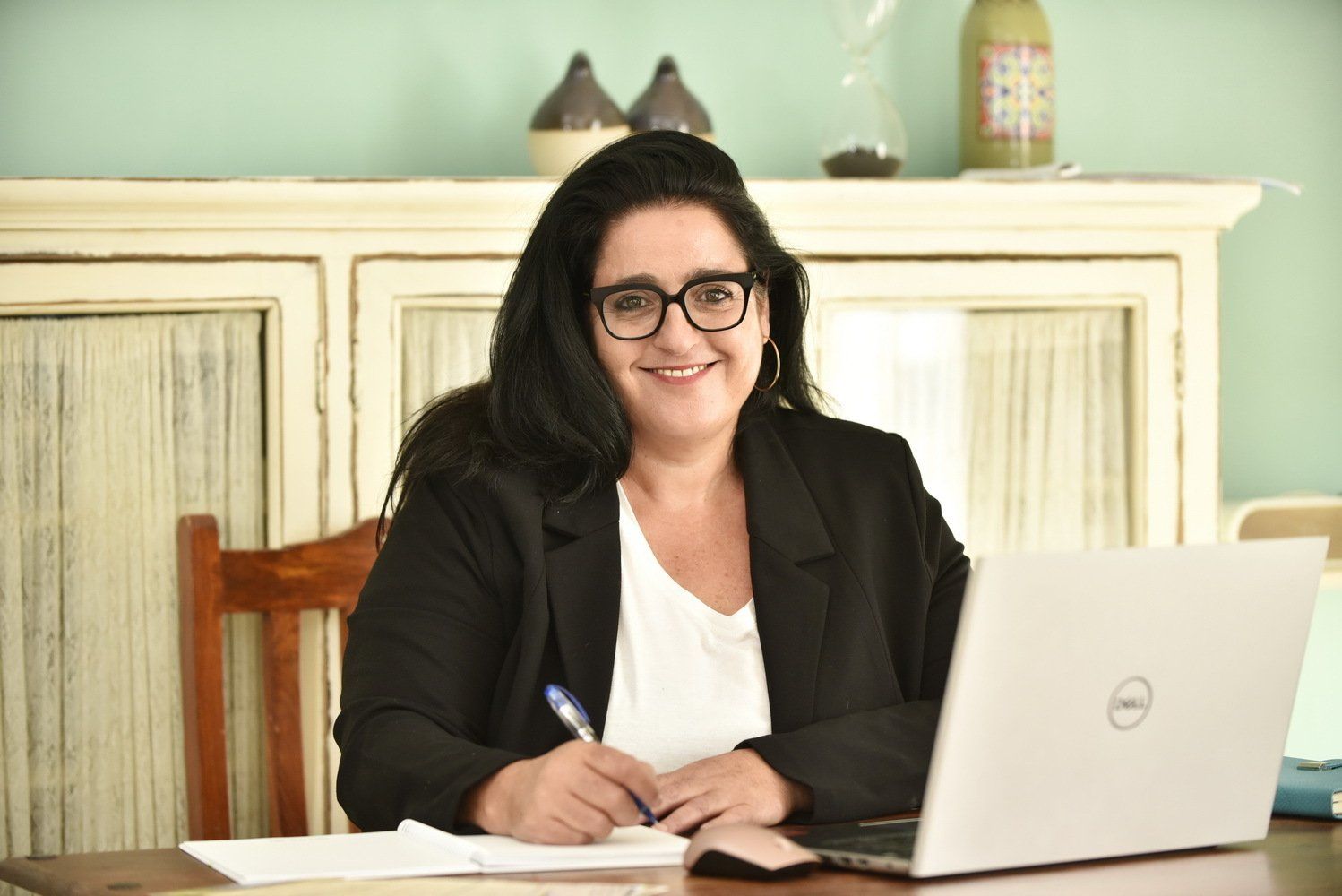 אישה יושבת ליד שולחן עבודה עם מחשב נייד ועט.