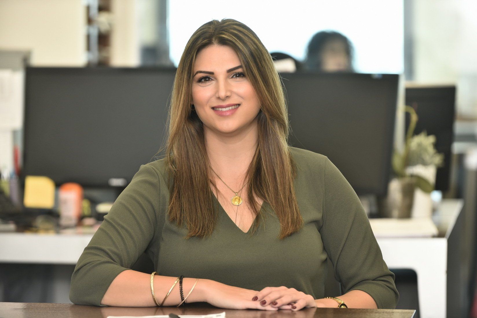 אישה יושבת ליד שולחן מול צג מחשב.