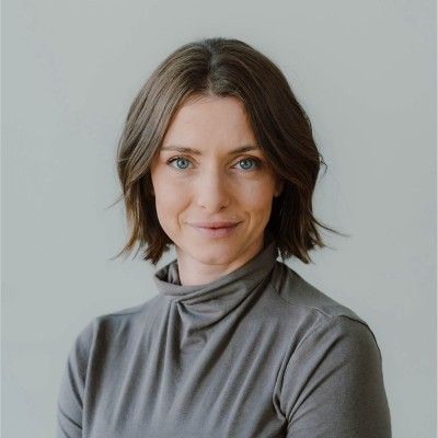 Woman with bobbed brown hair, wearing a gray turtleneck, smiling.