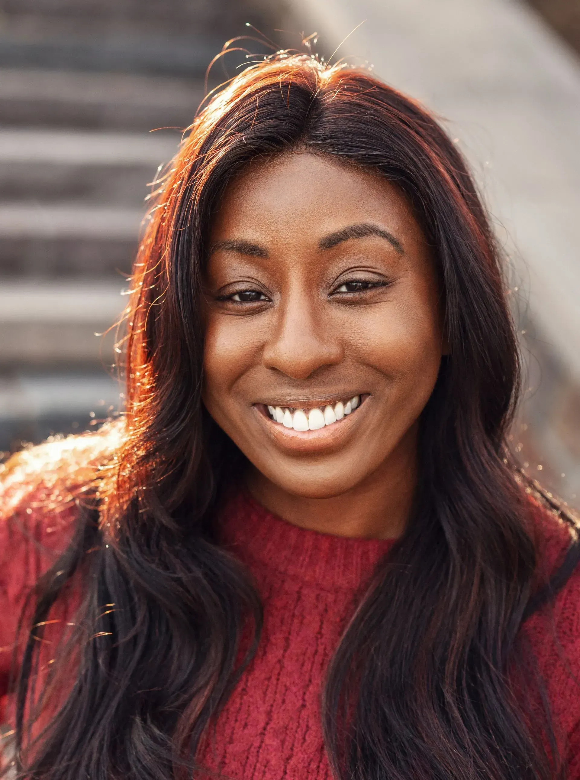 Smiling Black woman with long dark hair in red sweater.