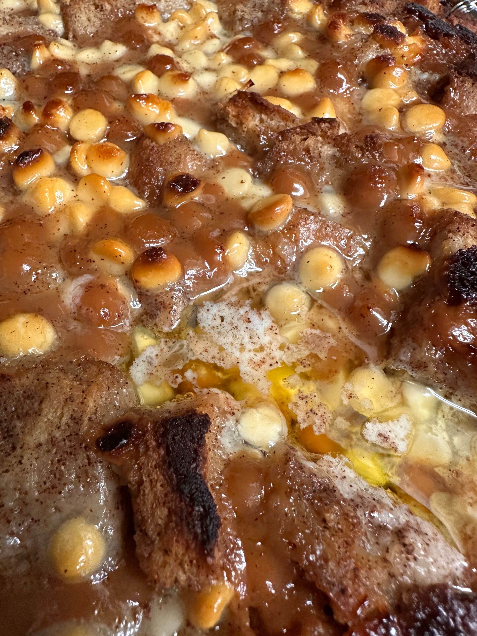 Close-up of a simmering bean stew with browned meat and melted cheese.