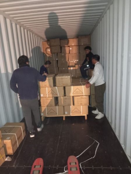 Un grupo de personas está de pie dentro de un contenedor de envío lleno de cajas.