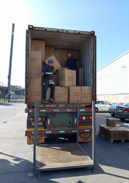 Dos hombres están cargando cajas en la parte trasera de un camión.