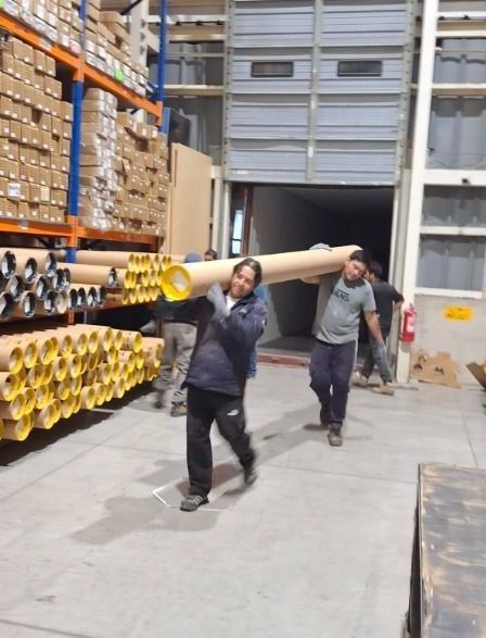 Un hombre lleva una tubería grande en un almacén.