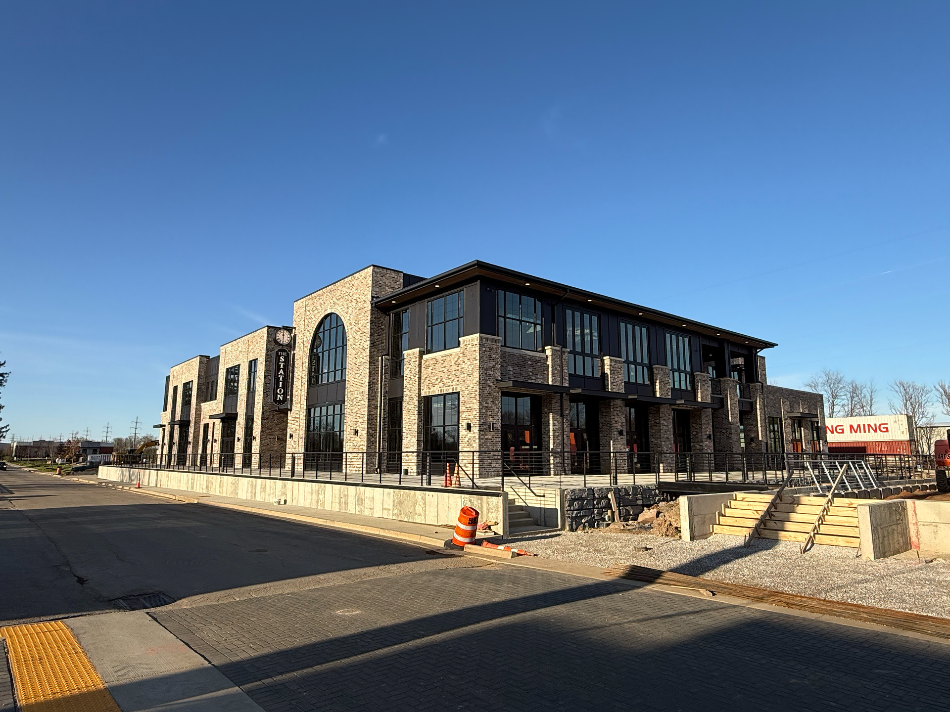 Modern brick building at dusk with lit windows, trees, and streetlights.