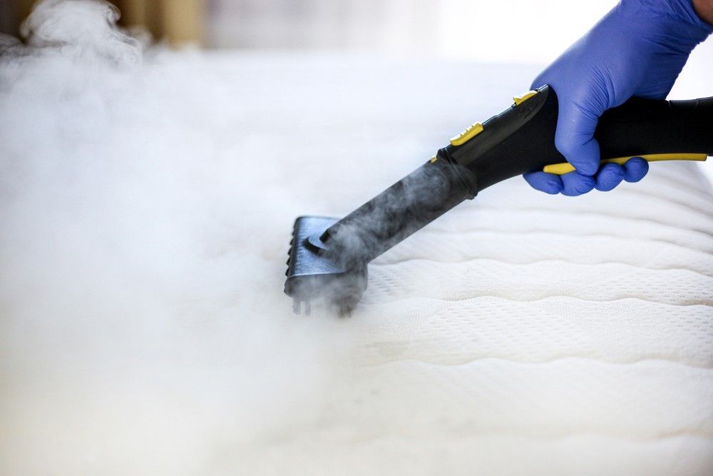 A Person is Cleaning a Mattress With a Steam Cleaner — Verdi Cleaning Services in Holt, ACT