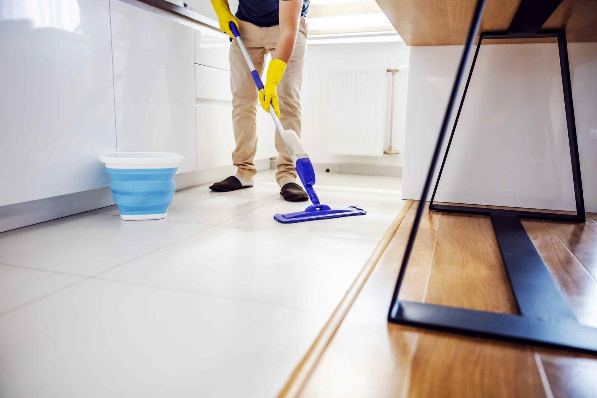 A Man is Cleaning the Floor in a Kitchen With a Mop — Verdi Cleaning Services in Holt, ACT