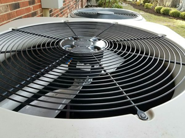 Close-up of a residential air conditioning unit's fan and protective grill.