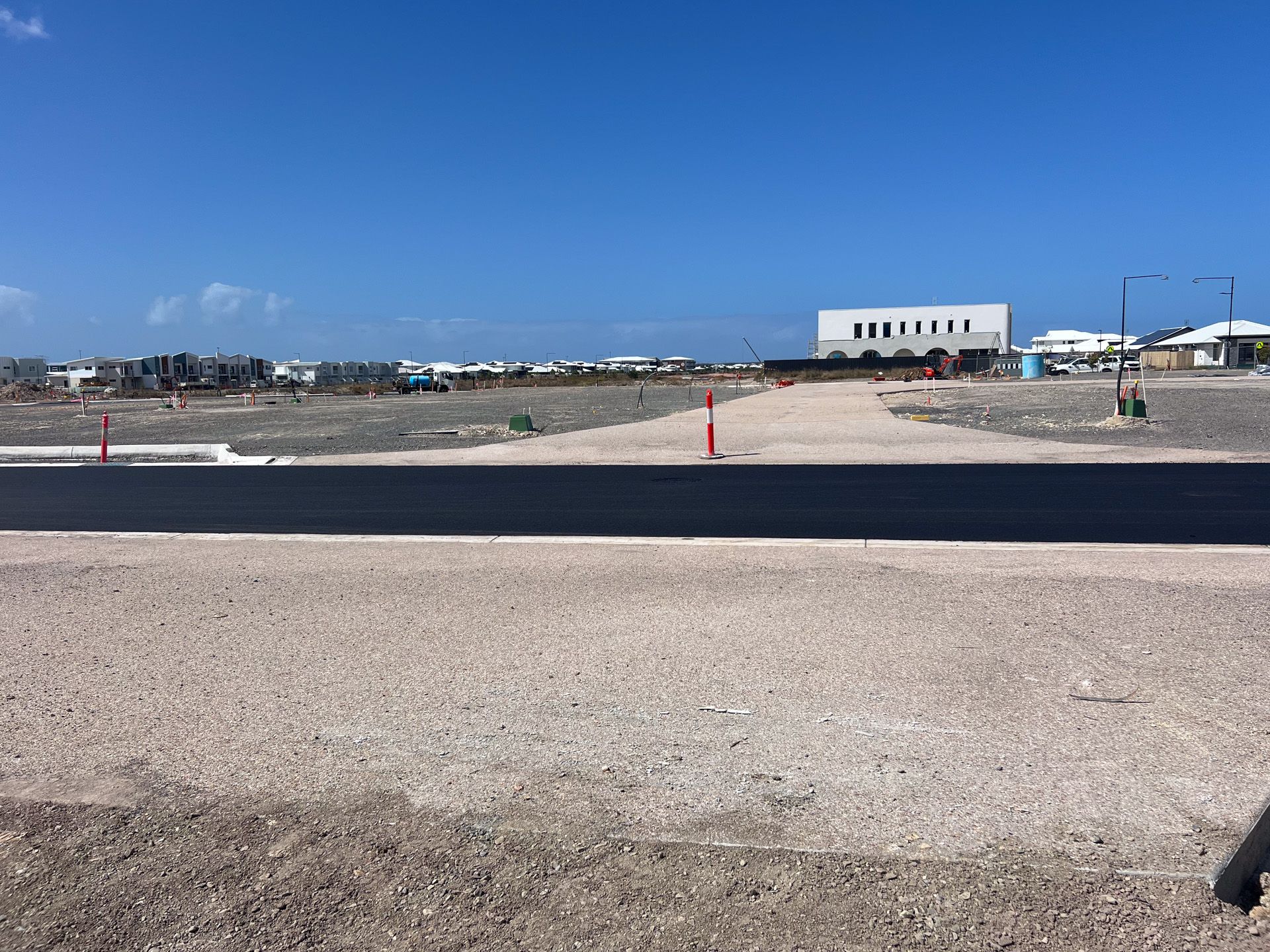 Construction site with gravel roads and building under construction; clear sky.
