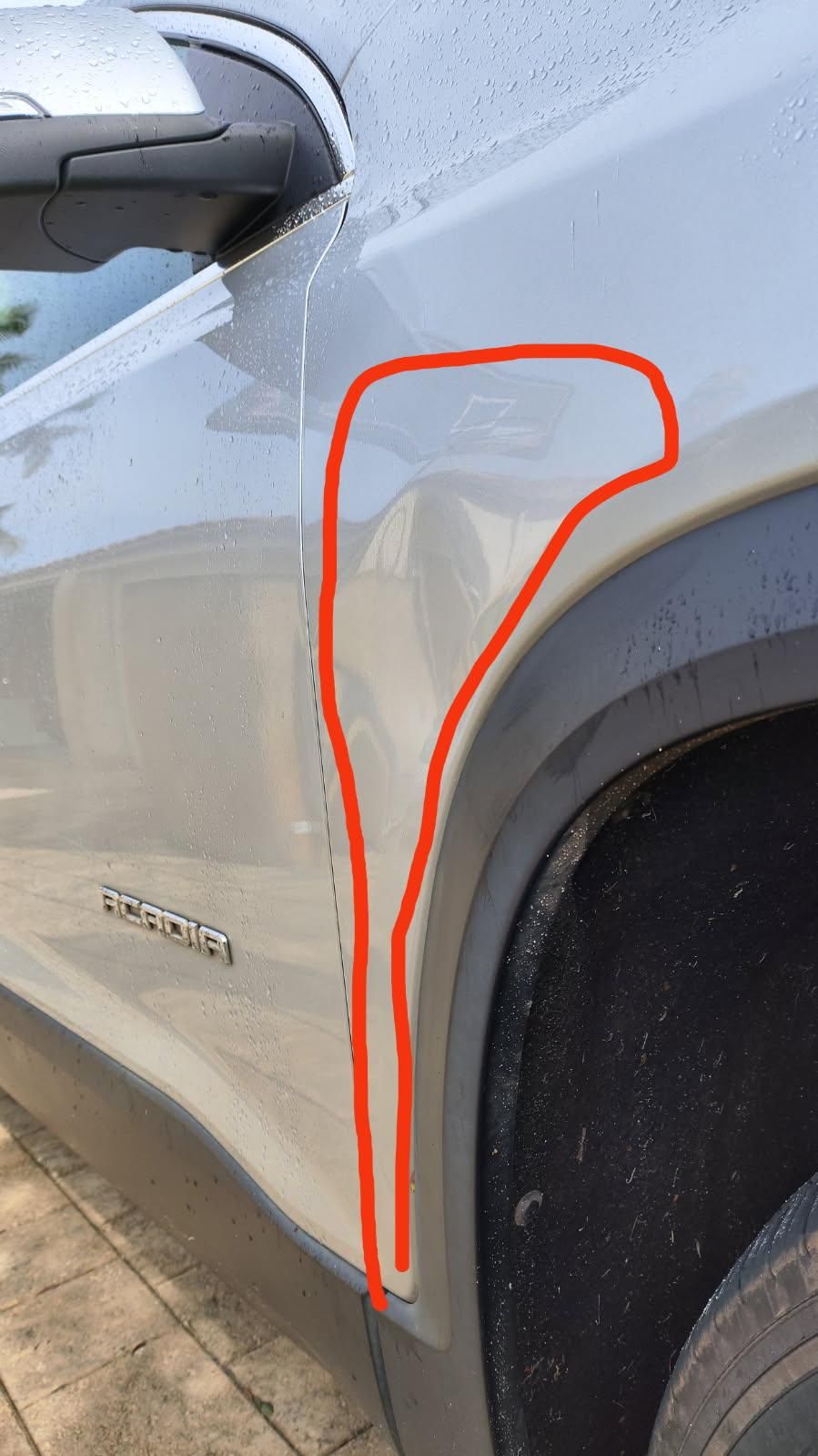 Silver car with dented front fender above the tire, near the headlight.