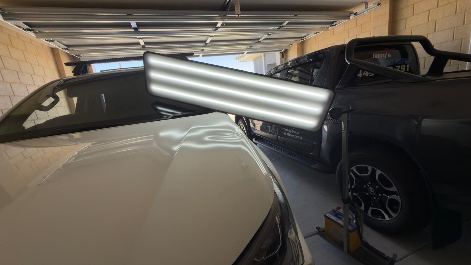 Black car with front-end damage, including a crumpled hood and broken bumper, on a concrete surface.