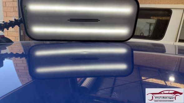 White car's rear side with a dent, likely from a collision, showing damage and a crack in the paint.