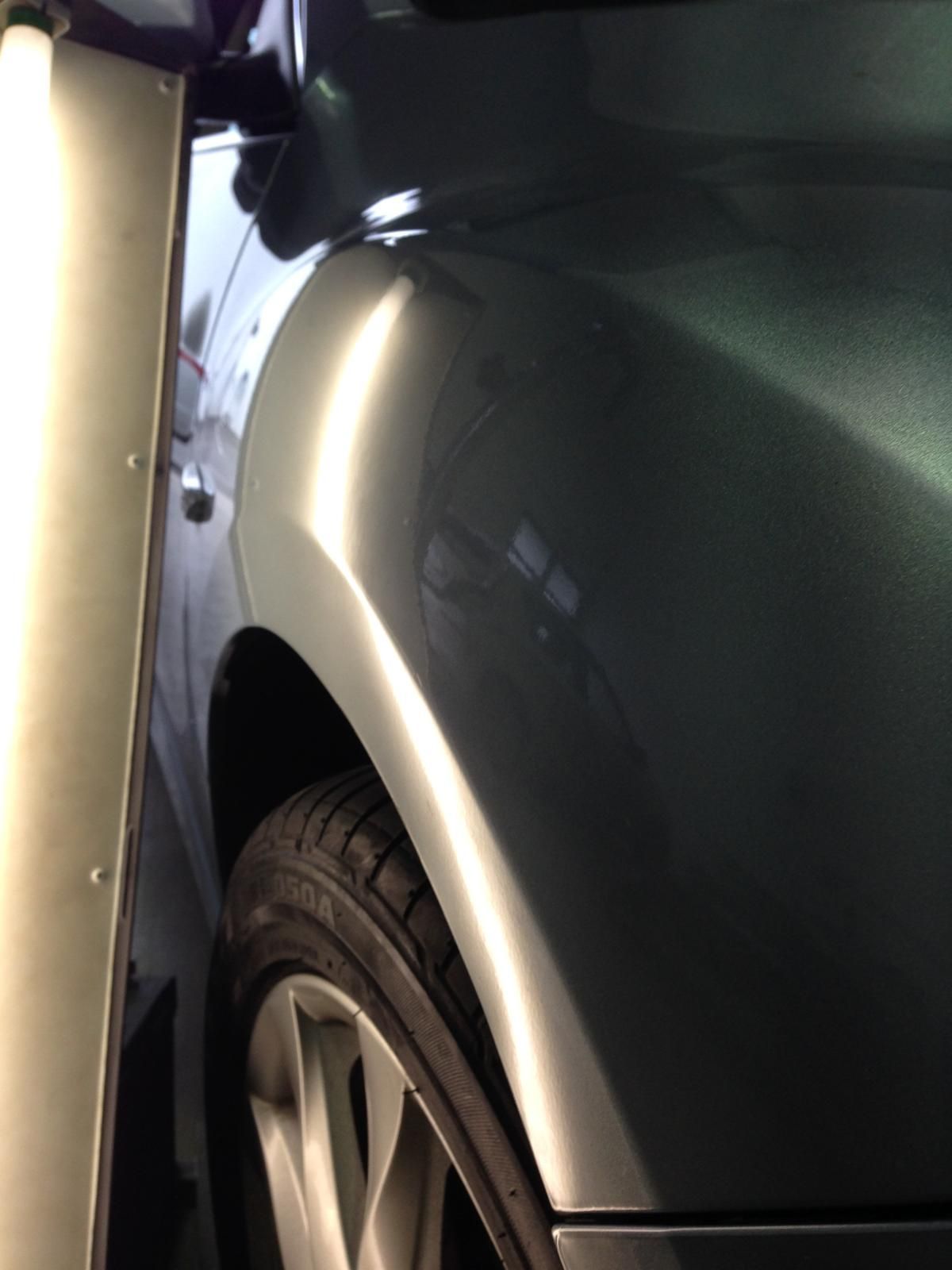 Tan car parked under a shaded structure; rear door and side visible.