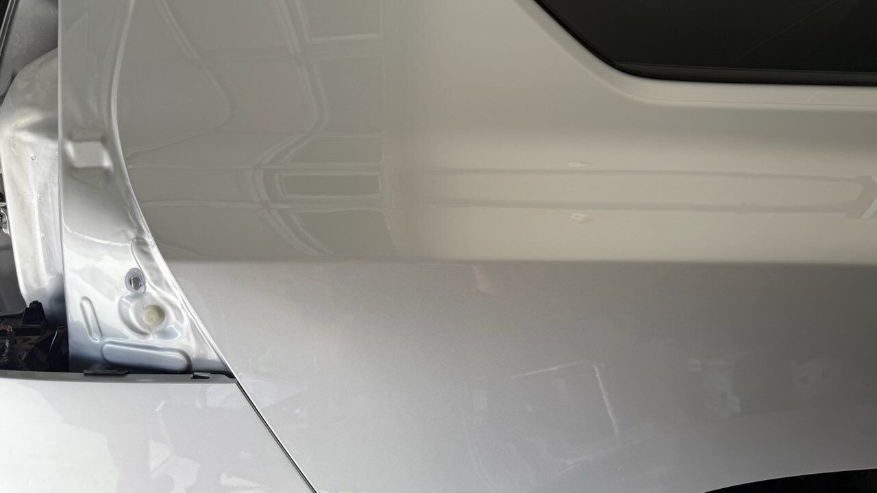 White car rear quarter panel with taillight, parked in driveway.