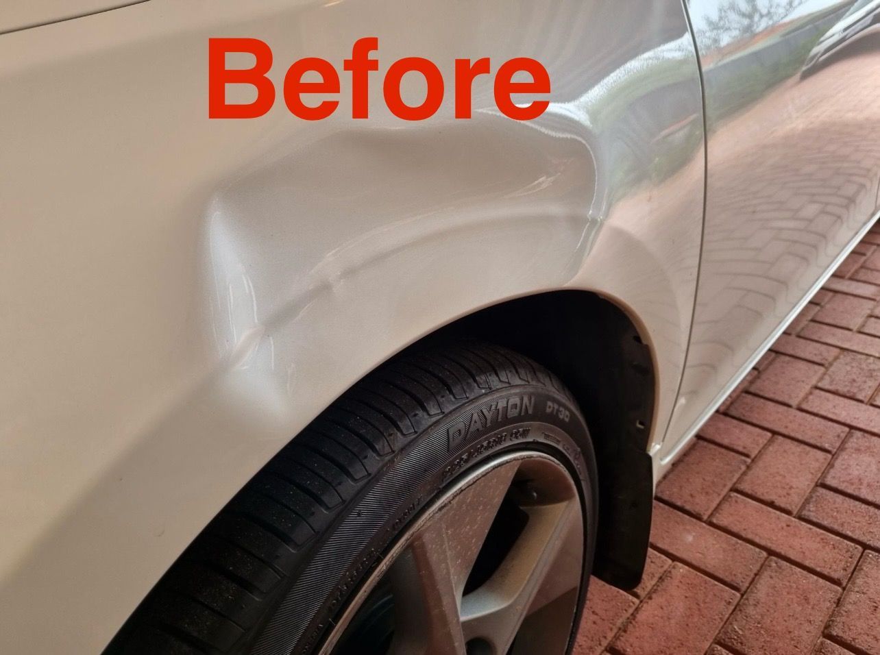 White car side with a large dent above the front tire, labeled 